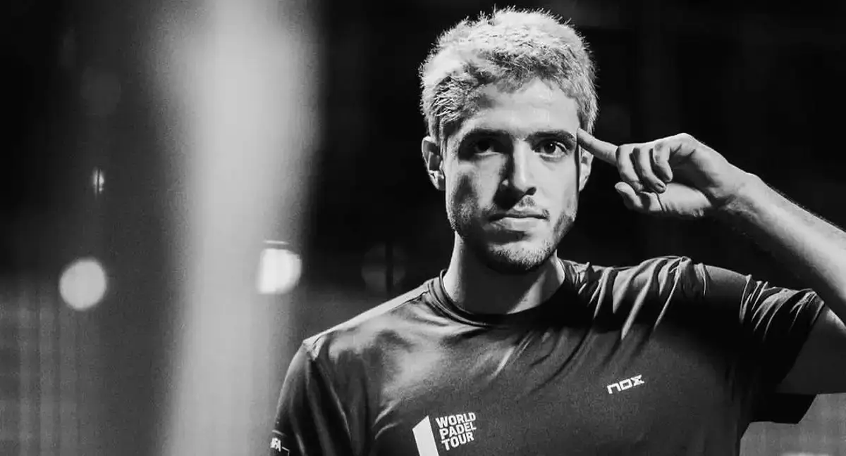 Agustín Tapia in a focused moment, gesturing to his head while wearing his World Padel Tour gear.