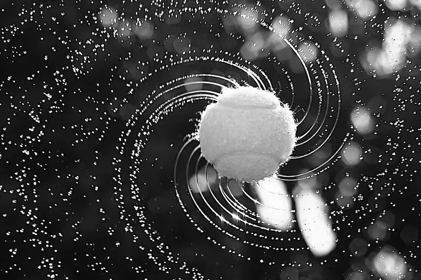 Close-up of a spinning padel ball creating a spiral effect with water droplets.