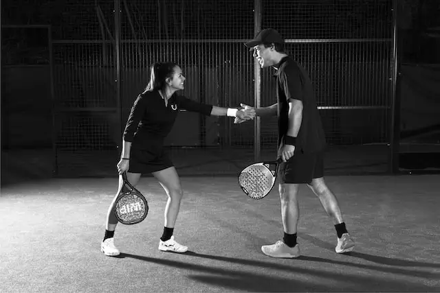 Two padel players shaking hands on the court after a match, showing good sportsmanship and teamwork.