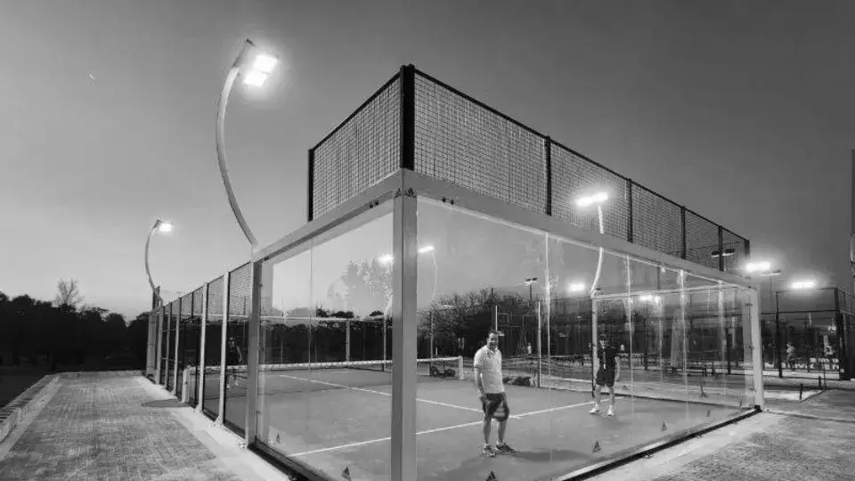 Padel court illuminated by tall, bright LED lights during evening play, enhancing visibility and creating a clear game environment.