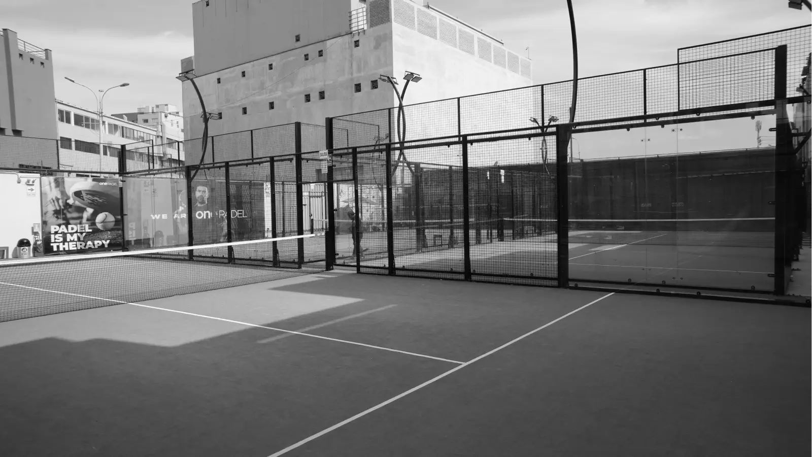 Empty padel courts with clean glass walls, sturdy fencing, and well-maintained surfaces under clear daylight conditions.